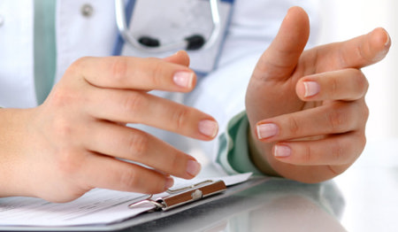 Leicht gestkulierende Hände einer Ärztin, auf einem Klemmbrett liegend.